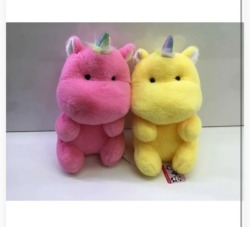 two round, chubby unicorn plush toys sitting side-by-side on a plain light surface.