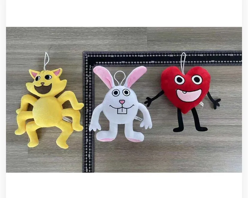 features three cartoon character plush toys with attached hanging strings, placed against a ruler grid on a wood-grain surface for size measurement.