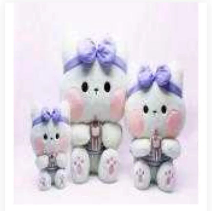features three white kitten plush toys in varying sizes arranged against a soft pink background.